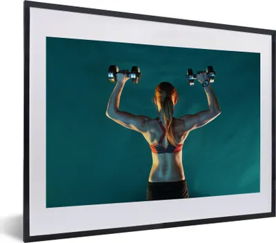 Produktbild von MuchoWow® MuchoWow® Gerahmtes Poster Eine Frau hält beim Fitness zwei Gewichte hoch 40x30 cm - Poster mit zchwarzem Bilderrahmen - Bilderrahmen - Poster im Rahmen