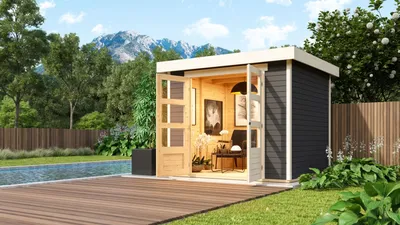 A modern garden shed with double doors open, revealing a furnished interior, situated next to a swimming pool and wooden deck in a backyard setting with mountains in the background.
