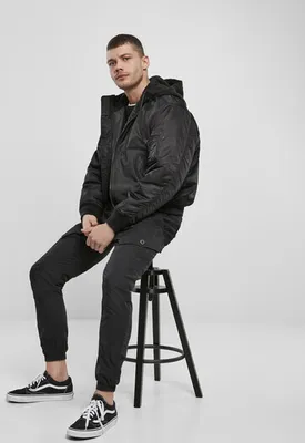 A man is sitting on a stool in a studio setting.