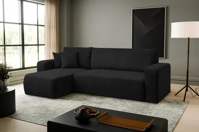 A modern living room with a black sectional sofa, a coffee table, and a floor lamp.