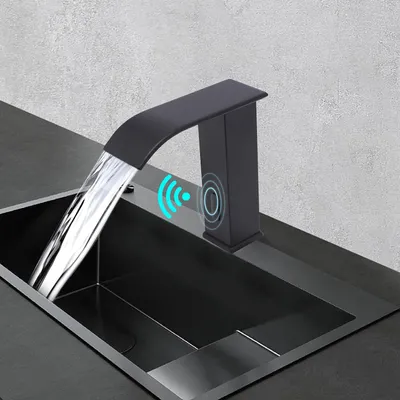 A black waterfall faucet with a sensor is shown in use over a black sink.