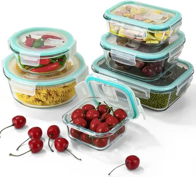 A collection of glass food storage containers filled with various food items and some loose cherries in the foreground.