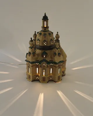 A lit-up ceramic model of the Frauenkirche church in Dresden, Germany, on a white background.