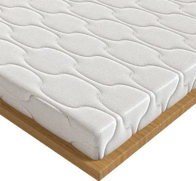 A close-up, angled view of a white mattress topper with a quilted pattern, resting on a wooden base.