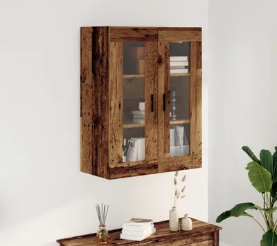 A wooden wall cabinet with glass doors is mounted on a white wall above a wooden console table.