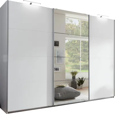 A white sliding door wardrobe with mirrored doors, reflecting a room interior with plants and pictures.