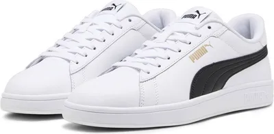 A pair of white Puma Smash sneakers with black accents and gold Puma branding.