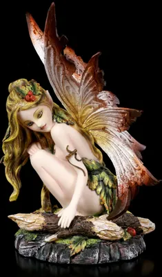 A fairy figurine sitting on a log.