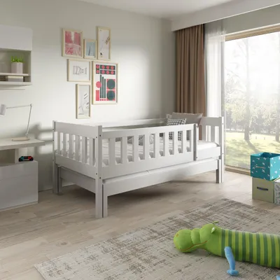 A child's bed in a room with a window and toys.