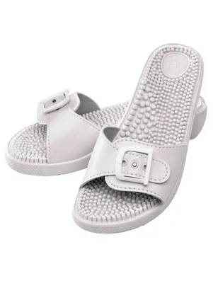 A pair of white massage slippers with a buckle detail and textured insoles.