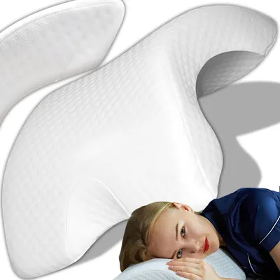 A woman is lying on a white pillow, with a large white orthopedic pillow behind her.