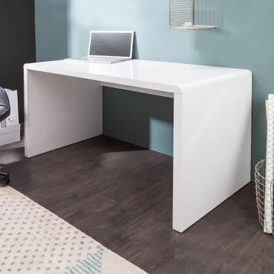 A modern white high-gloss desk with a laptop on it, set against a teal wall and dark wooden floor.