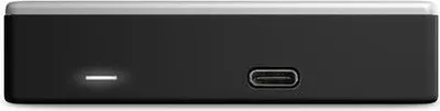 The image shows the back or side of a black external hard drive with a silver top edge. Two ports are visible: a USB-C port and a smaller port with a light indicator.