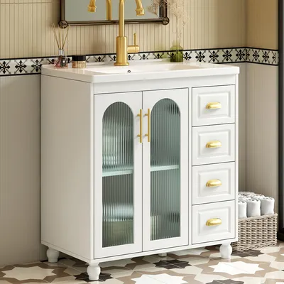 A white bathroom vanity with a ceramic sink and gold fixtures, set against a tiled wall.