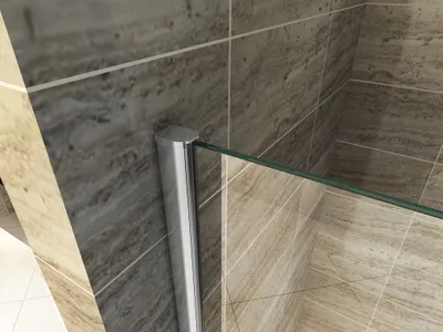 A close-up view of a shower enclosure corner with tiled walls.