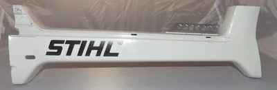 A white Stihl part with the Stihl logo on it, lying on a light gray surface.