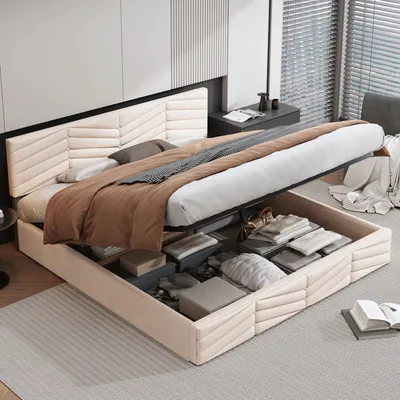 A beige upholstered storage bed with the mattress lifted to reveal storage compartments filled with folded linens and other items.