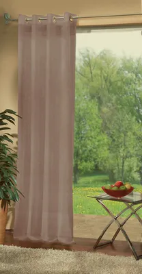 A sheer curtain hangs in front of a window with a view of trees and grass. A small table with fruit is visible.