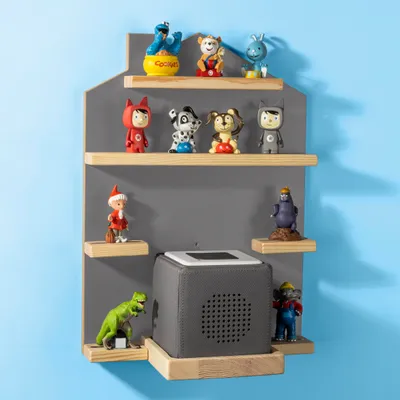 A wall-mounted shelf unit displaying various small figurines and a gray cube-shaped speaker.