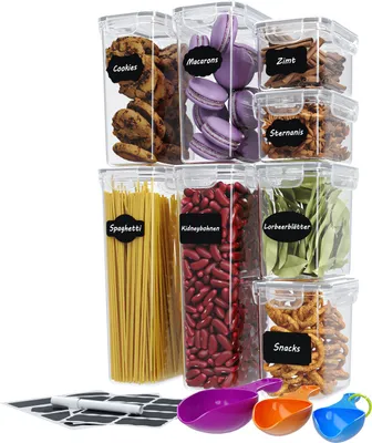 A collection of clear plastic food storage containers filled with various food items and labeled with chalk labels.