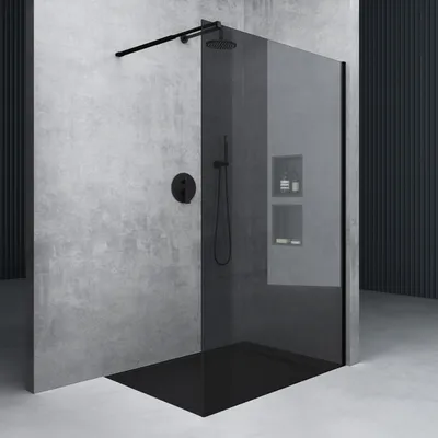 A modern bathroom shower enclosure with a black glass wall and black fixtures against a concrete wall.