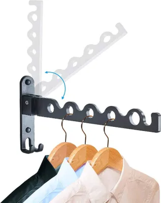 A wall-mounted drying rack with clothes hangers holding shirts.