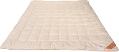 A cream-colored quilted blanket laid out on a white background.