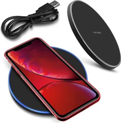 A red smartphone is placed on a black wireless charging pad, with a black USB cable coiled nearby and another black wireless charger in the background.