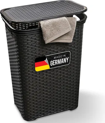 A black laundry basket with a lid and two folded towels hanging from the edge. A "Made in Germany" label is visible on the front.