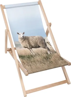 A wooden deck chair with a printed image of a sheep on a grassy field.