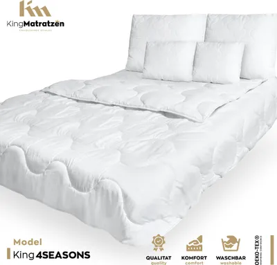 A white duvet and pillows are arranged on a bed, presented in a studio setting with a white background.