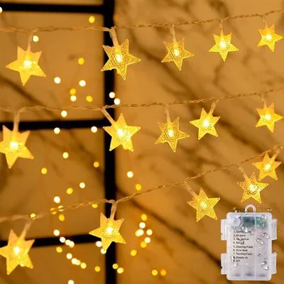Immagine prodotto di Catena luminosa LED Unyqoos® – 6 metri, 40 LED a forma di stella con luce bianca calda, alimentazione a batteria (3 batterie AA), 8 modalità di illuminazione, grado di protezione IP65 (resistente all'acqua), adatta per interni ed esterni, classe di efficienza energetica A+++