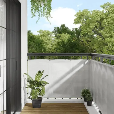 A balcony with a grey privacy screen, plants, and a view of trees.