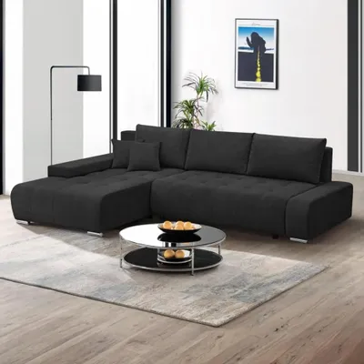 A modern living room with a black sectional sofa and a round coffee table.