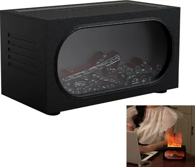 A person is using a laptop at a desk, with a small decorative fireplace diffuser on the desk emitting LED flames.