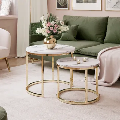 A living room scene with a green sofa, coffee tables, and a vase of flowers.