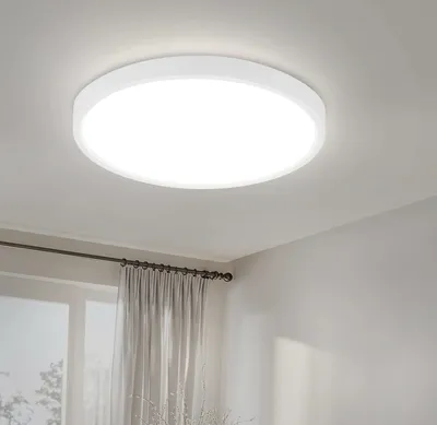 A white, circular LED ceiling light is mounted on a white ceiling.