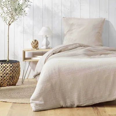 A bedroom scene with a bed, nightstand, and plant.