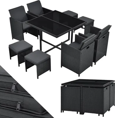 A black polyrattan garden furniture set with a glass-topped table, chairs, and stools, arranged on a white background.