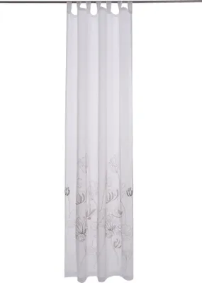 A white curtain with a floral design is hanging from a curtain rod.