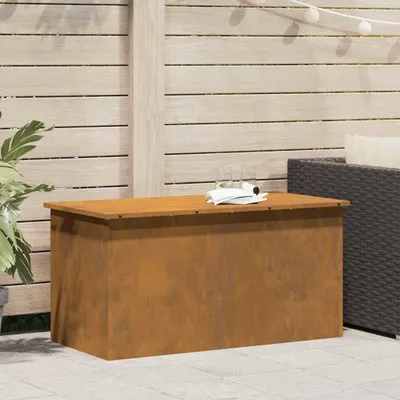 An outdoor storage box sits on a patio next to a wicker chair and a plant.