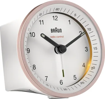 A close-up, studio shot of a Braun radio-controlled alarm clock with a pink bezel and white face.