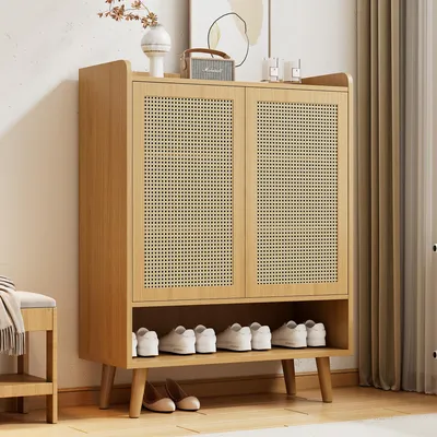 A wooden shoe cabinet with rattan doors and shelves, displaying shoes and decorative items on top.