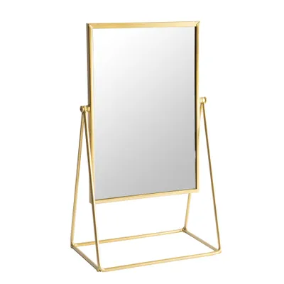 A freestanding gold tabletop mirror against a white background.