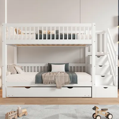 A white bunk bed with a pull-out trundle bed and stairs with drawers, set up in a bedroom.