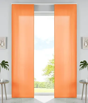 Two orange panel curtains are shown hanging in front of a window with a view of trees and sky.