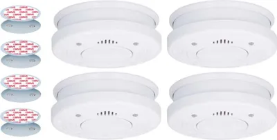 Four white smoke detectors are arranged in a 2x2 grid, with four adhesive mounting plates shown to the left.