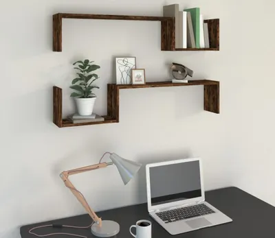 A desk setup with a laptop, lamp, and coffee mug, with two wall shelves mounted above.