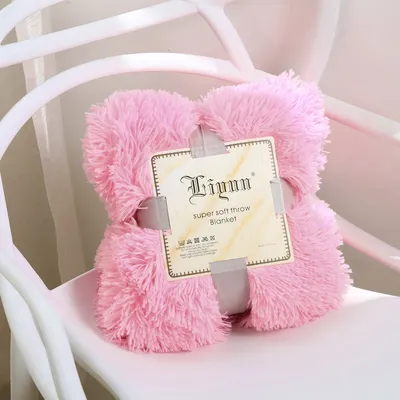 A pink fluffy blanket folded and placed on a white chair.