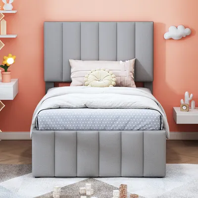 A child's bedroom with a gray upholstered bed as the main focus. The bed is made with white and blue polka-dot bedding and includes decorative pillows.